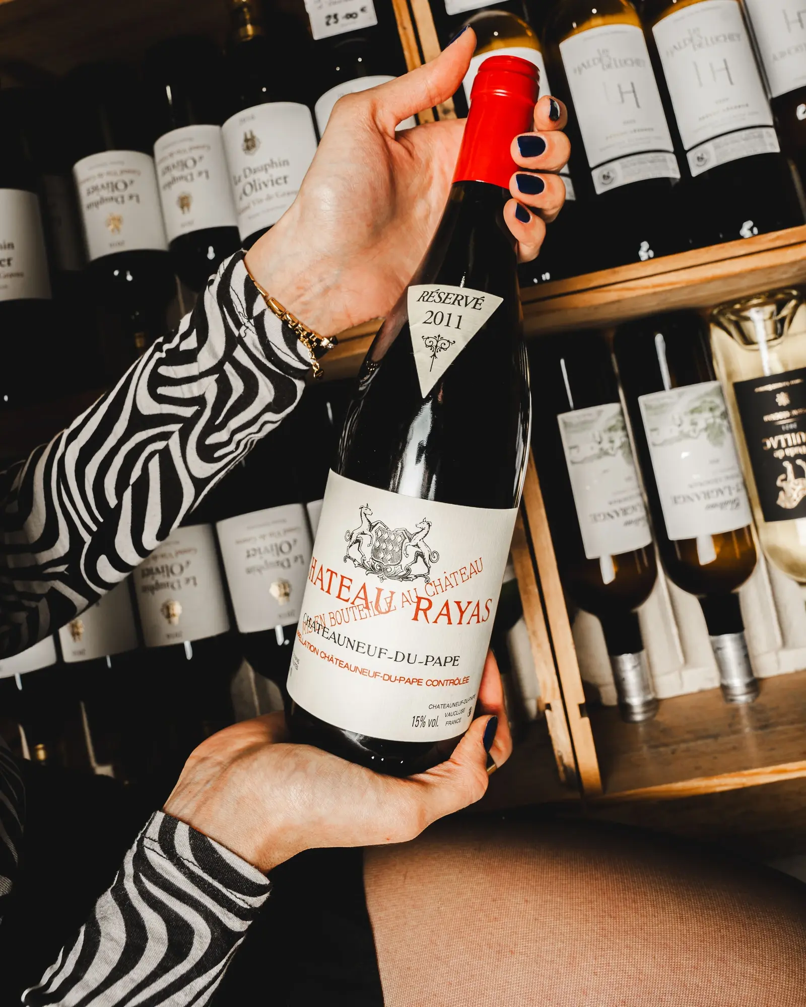 Une main sort une bouteille de rouge d’un casier de la cave.