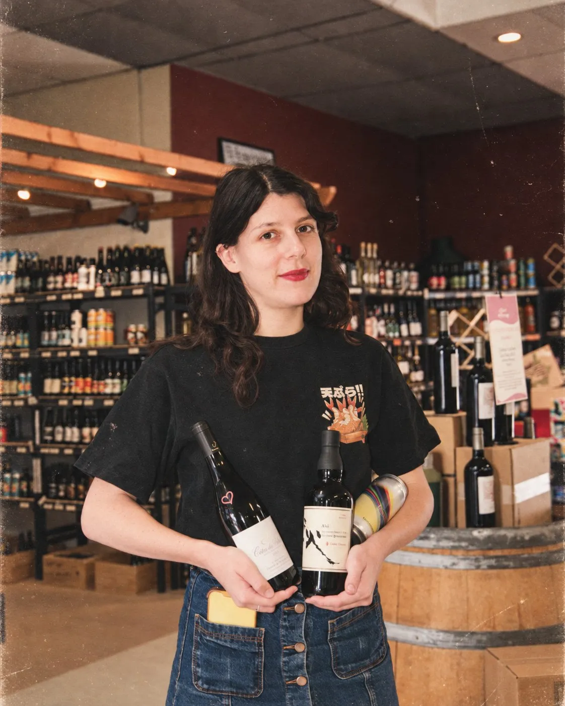 Camille tient trois bouteilles au milieu des rayons de la cave