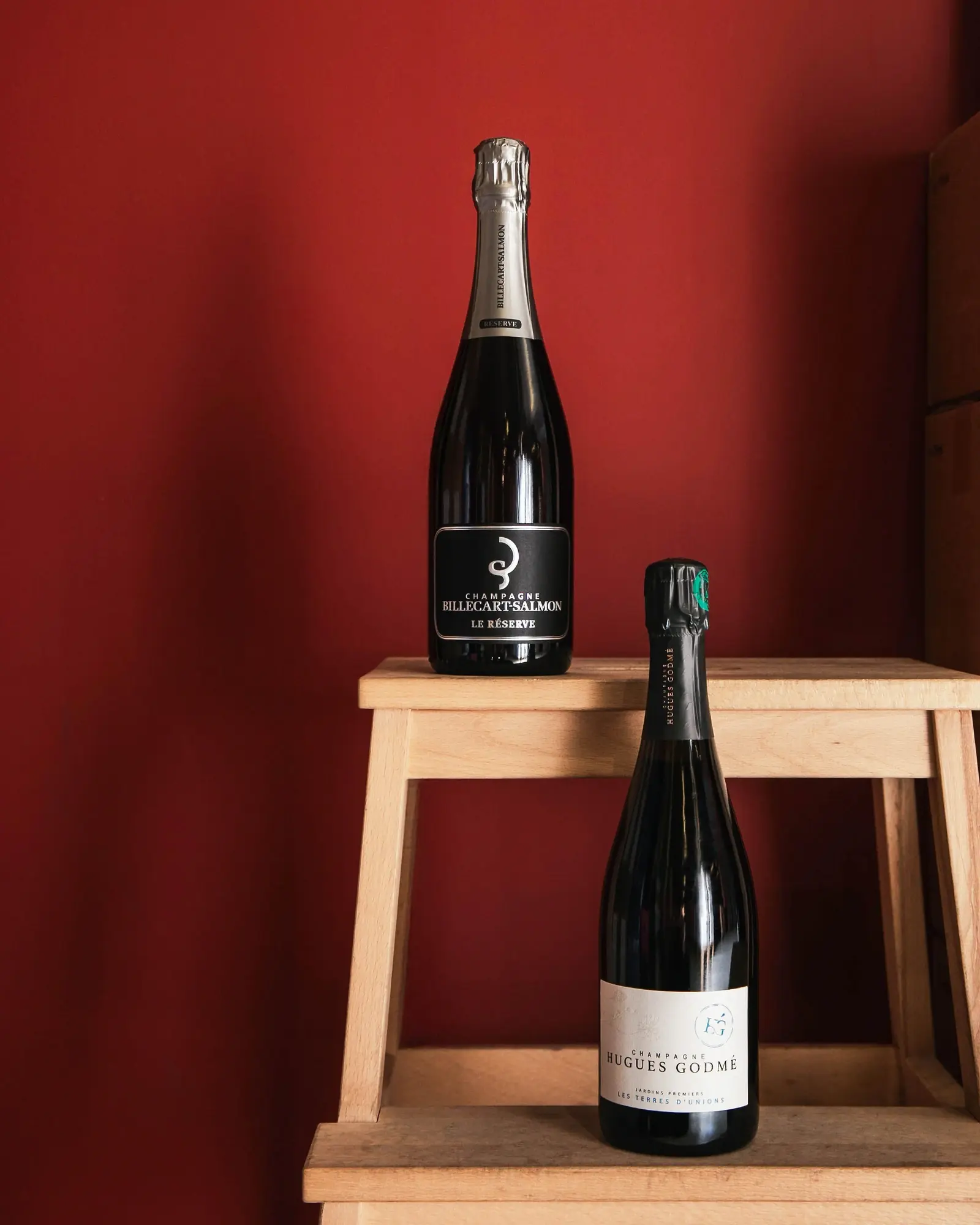Un champagne Billecart-Salmon et un champagne Hugues Godmé posés sur un escabeau en bois.