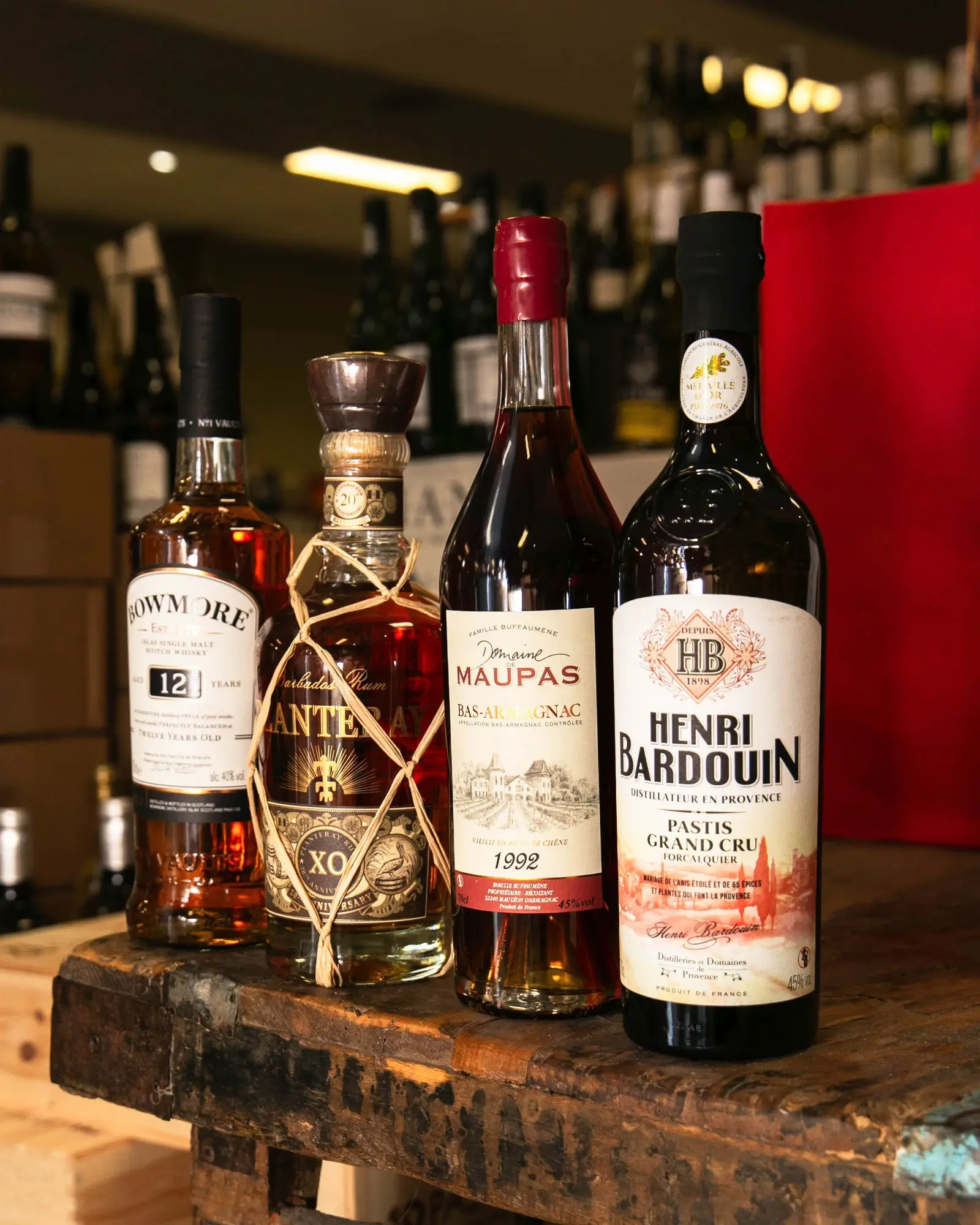Un whisky Bowmore, un rhum Plantation XO, un bas-armagnac Maupas 1992 et un pastis Henri Bardouin sur une table en bois de la cave.